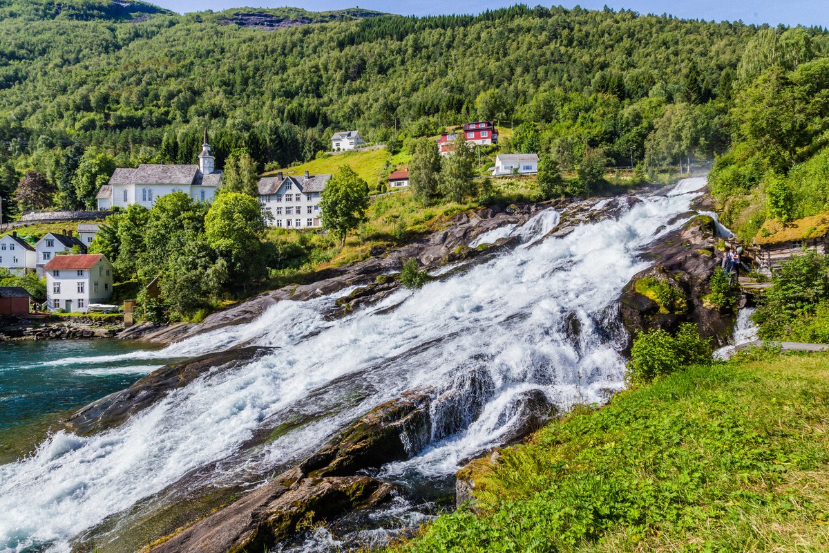 Hellesyltfossen in the middle of Hellesylt, with the church and wooden houses behind