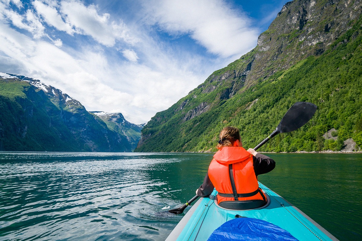 Kayaker in a life jacket on the Geirangerfjord between steep mountainsides