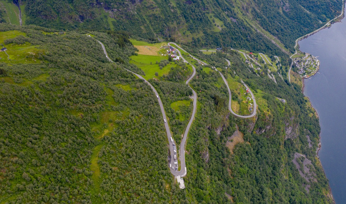 The hairpin bends of Ørnevegen above the Geirangerfjord with cars and motorhomes at the viewpoint
